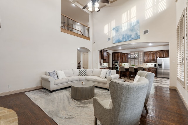 living room featuring a towering ceiling, ceiling fan, dark wood-type flooring, and sink