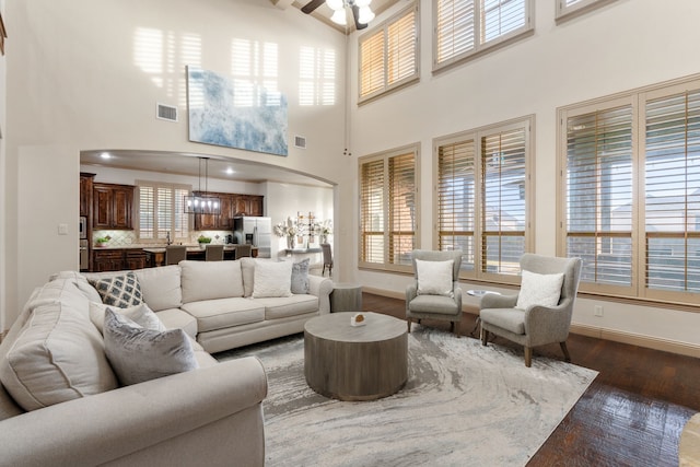 living room with a towering ceiling, dark hardwood / wood-style floors, and ceiling fan