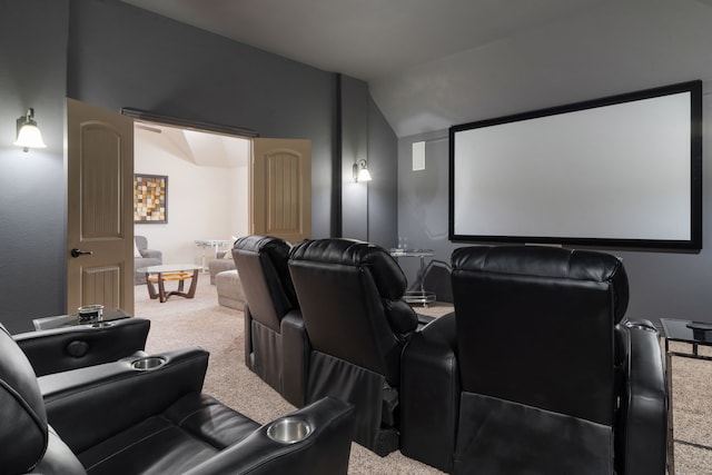 carpeted home theater featuring vaulted ceiling