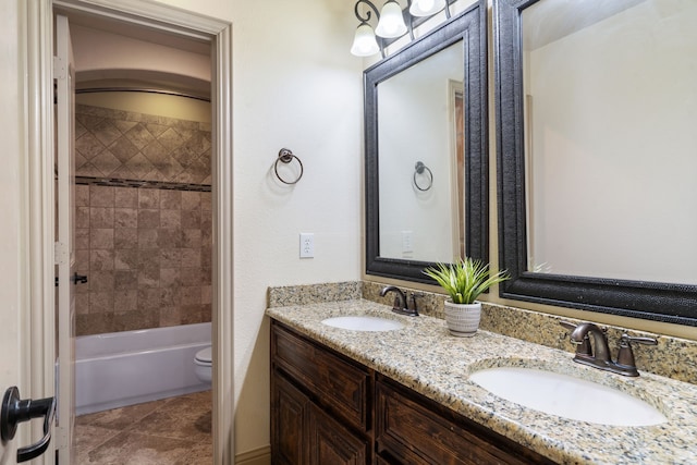 full bathroom with tiled shower / bath, vanity, and toilet