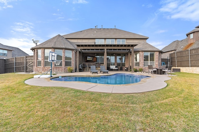 rear view of house with a fenced in pool, a yard, a patio, and an outdoor kitchen