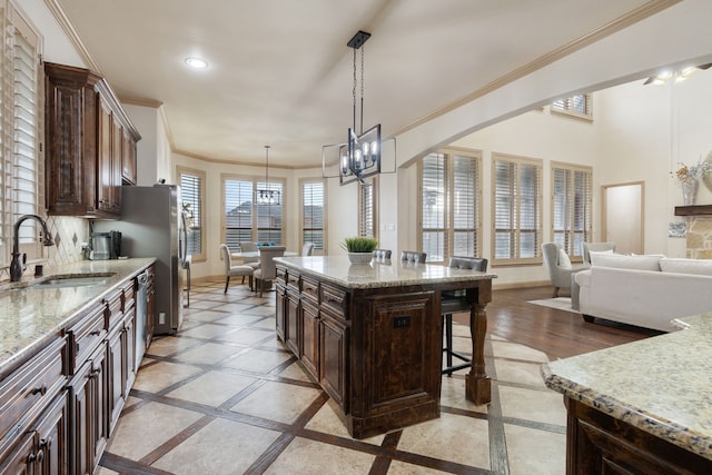 kitchen with dark brown cabinets, a kitchen island, stainless steel dishwasher, and sink