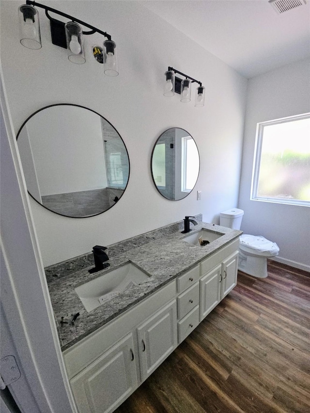 full bathroom with wood finished floors, a sink, double vanity, and toilet