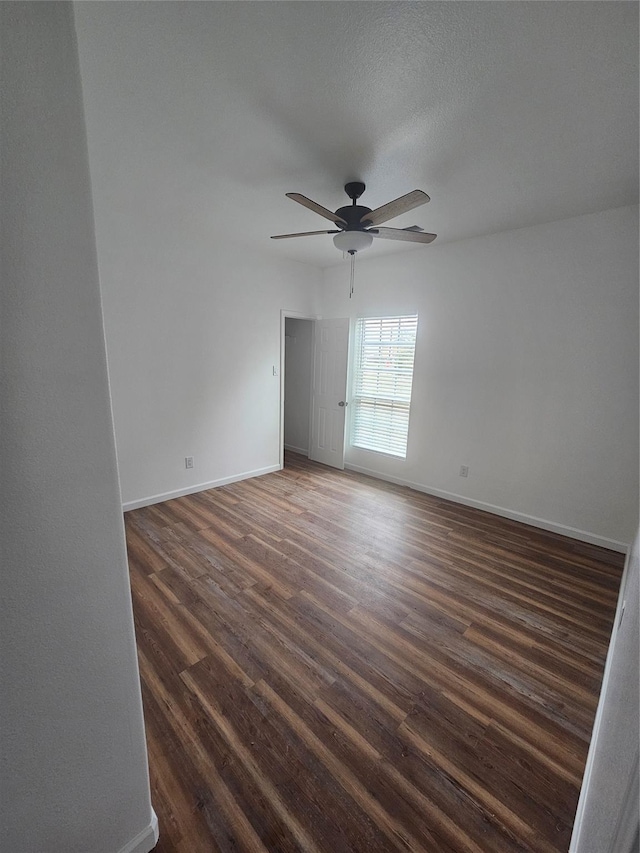 spare room with a textured ceiling, ceiling fan, and dark wood-type flooring