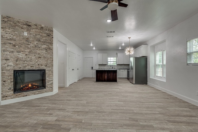 kitchen featuring a kitchen island, pendant lighting, light hardwood / wood-style flooring, white cabinets, and stainless steel refrigerator