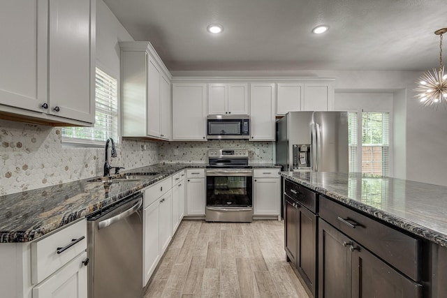 kitchen featuring pendant lighting, white cabinetry, sink, dark stone countertops, and stainless steel appliances