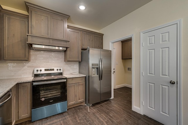 kitchen with dark hardwood / wood-style floors, light stone counters, decorative backsplash, and appliances with stainless steel finishes