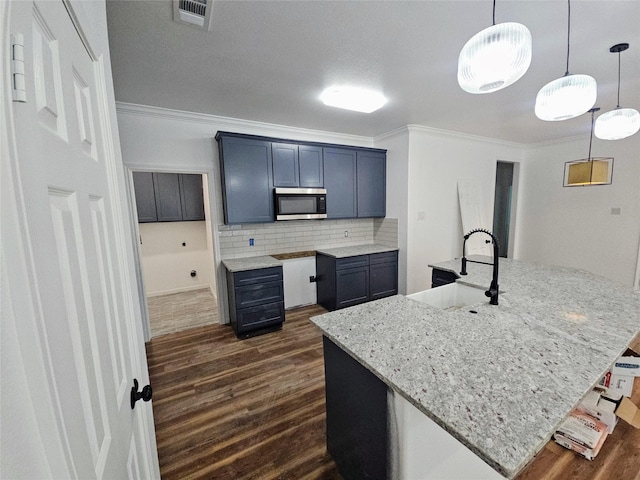kitchen with dark wood-style floors, a sink, stainless steel microwave, visible vents, and crown molding
