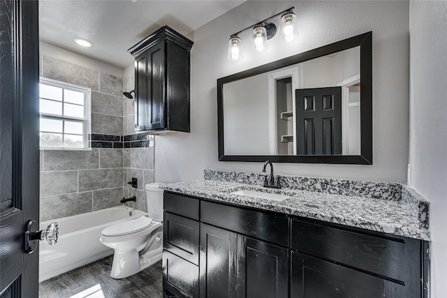 full bathroom with toilet, vanity, wood-type flooring, and tiled shower / bath