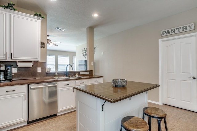 kitchen with dishwasher, sink, ceiling fan, a kitchen bar, and white cabinetry