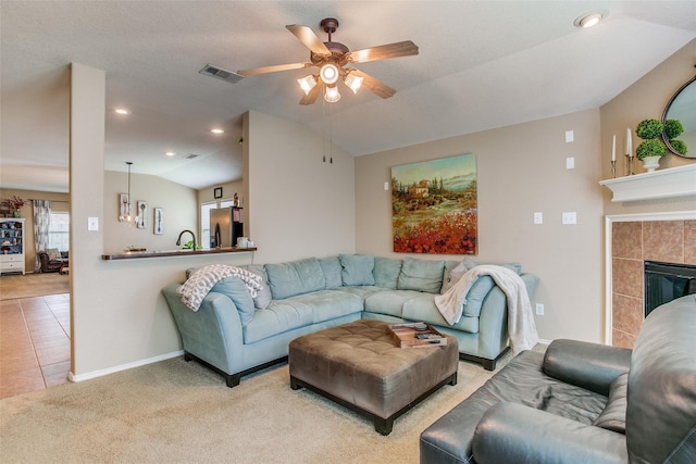 living room featuring lofted ceiling, sink, ceiling fan, carpet, and a tiled fireplace