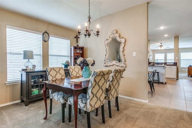 carpeted dining area featuring ceiling fan with notable chandelier and sink