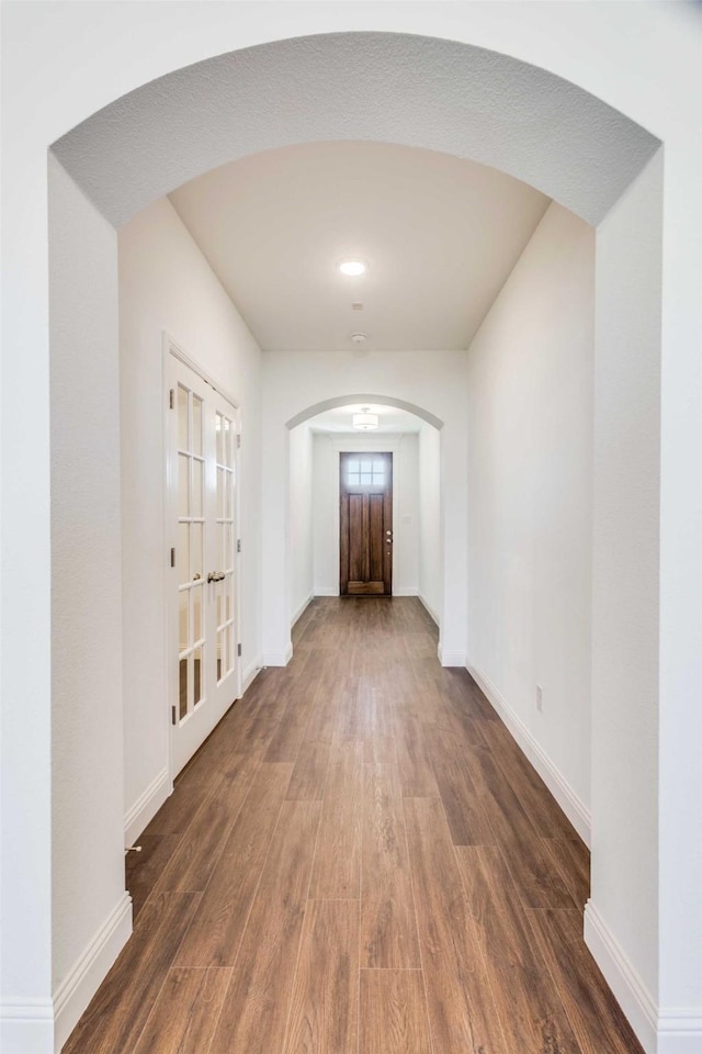 interior space featuring baseboards, arched walkways, and dark wood-style flooring