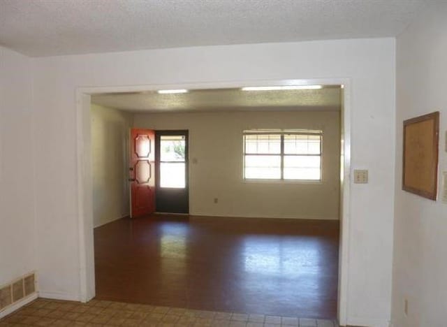 unfurnished room with a textured ceiling and dark hardwood / wood-style floors