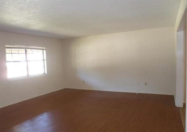 empty room with a textured ceiling and dark wood-type flooring