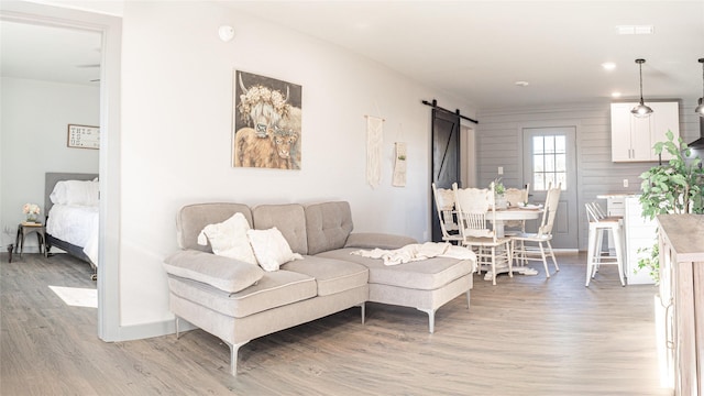 living room with hardwood / wood-style floors, a barn door, and wood walls