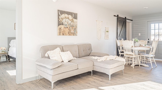 living room with a barn door and light wood-type flooring