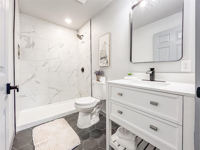 bathroom featuring tile patterned flooring, a tile shower, vanity, and toilet