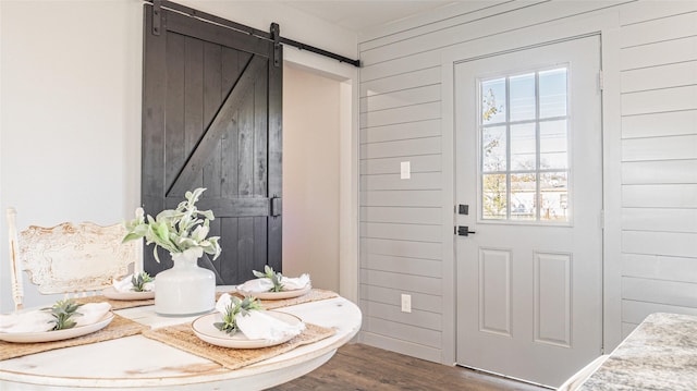 interior space featuring a barn door, dark hardwood / wood-style floors, and wooden walls