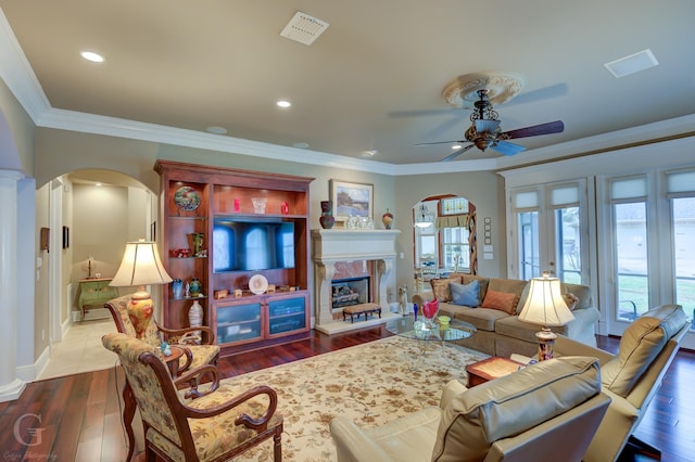 living room featuring ceiling fan, wood-type flooring, ornamental molding, and a premium fireplace