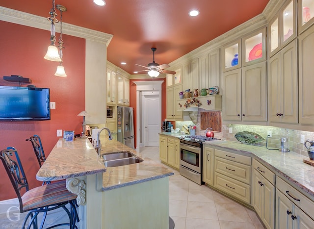 kitchen with sink, hanging light fixtures, a kitchen breakfast bar, backsplash, and appliances with stainless steel finishes