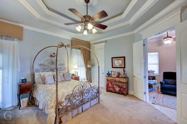 bedroom with a raised ceiling, ceiling fan, light colored carpet, and ornamental molding