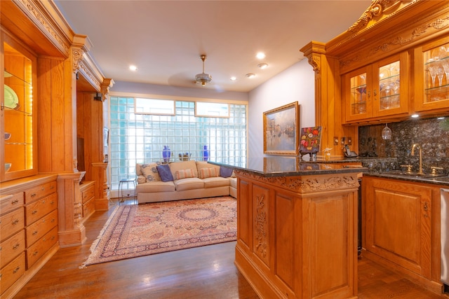 kitchen featuring decorative backsplash, wood-type flooring, sink, and dark stone counters