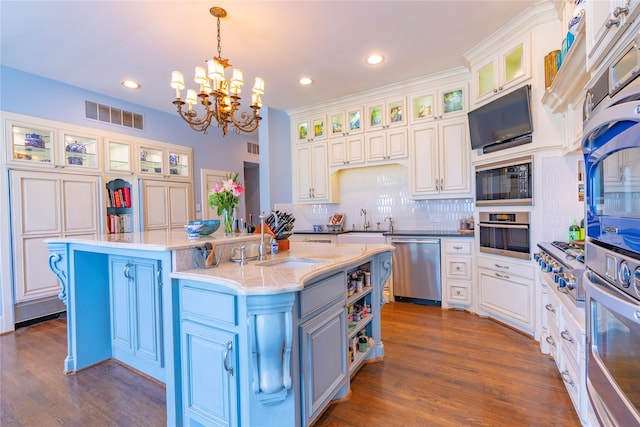 kitchen featuring stainless steel appliances, a kitchen island with sink, dark wood-type flooring, pendant lighting, and white cabinetry