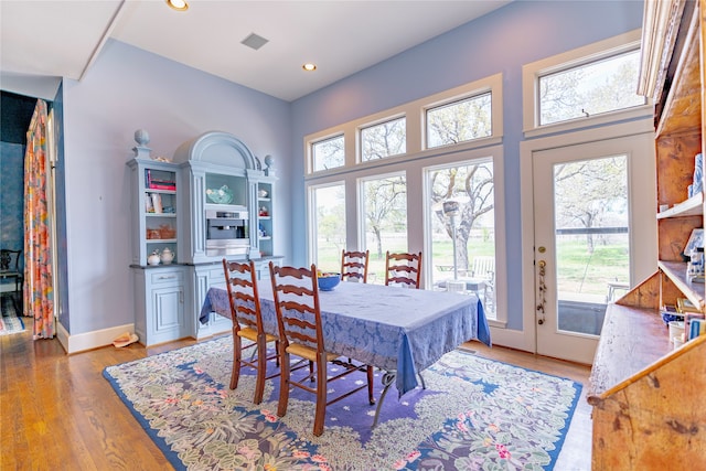 dining space with plenty of natural light, a towering ceiling, and wood-type flooring