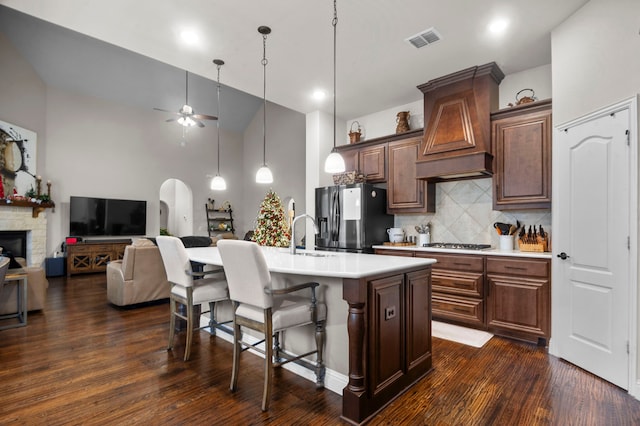 kitchen featuring a center island with sink, dark hardwood / wood-style floors, ceiling fan, a towering ceiling, and stainless steel appliances