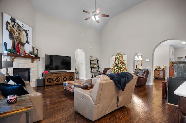 living room with dark hardwood / wood-style floors, ceiling fan, a fireplace, and high vaulted ceiling