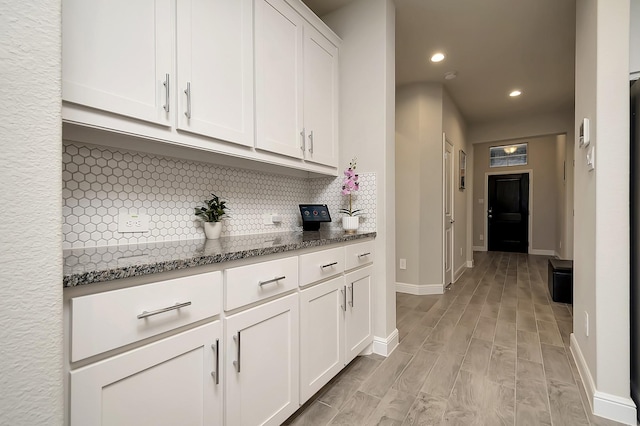 interior space with stone counters, recessed lighting, backsplash, white cabinets, and light wood-type flooring