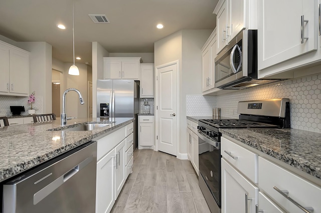 kitchen with light wood-style flooring, stainless steel appliances, a sink, visible vents, and white cabinets