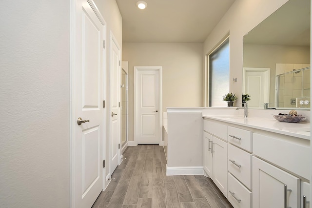 bathroom with a shower stall, baseboards, wood finished floors, and vanity