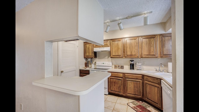 kitchen with sink, light tile patterned floors, white appliances, kitchen peninsula, and a textured ceiling