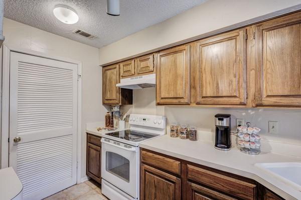 kitchen with sink, white electric range, and a textured ceiling