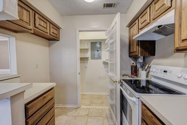 kitchen with a textured ceiling, white electric stove, and electric panel