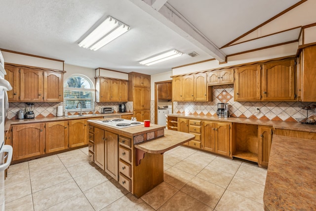 kitchen with a center island, light tile patterned flooring, lofted ceiling with beams, and sink