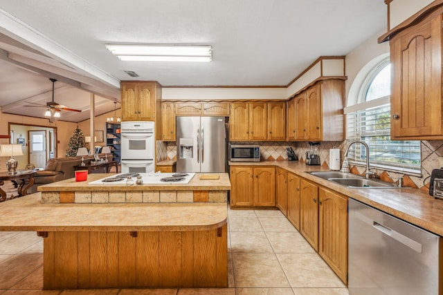 kitchen with stainless steel appliances, ceiling fan, sink, a center island, and lofted ceiling