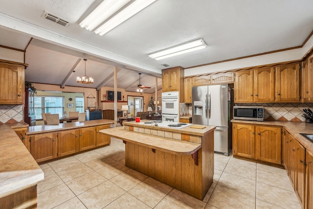 kitchen featuring ceiling fan with notable chandelier, stainless steel appliances, lofted ceiling with beams, decorative light fixtures, and a kitchen island