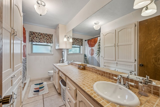 bathroom with tile patterned floors, vanity, toilet, and curtained shower