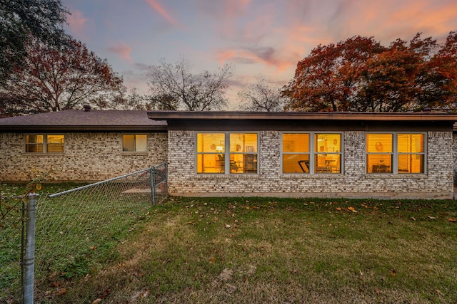 back house at dusk with a lawn