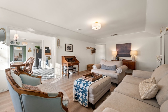 living area featuring light wood finished floors, baseboards, and visible vents