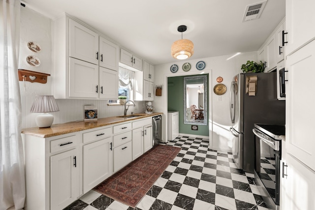 kitchen with dark floors, stainless steel appliances, visible vents, white cabinets, and a sink