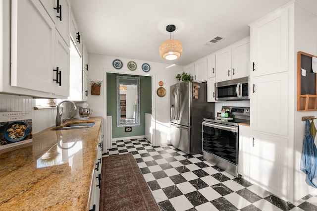 kitchen featuring visible vents, white cabinets, dark floors, stainless steel appliances, and a sink