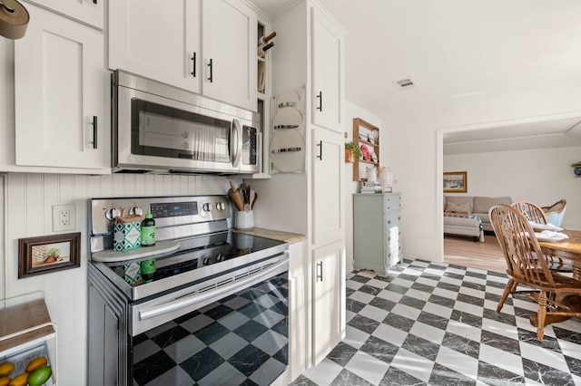 kitchen featuring appliances with stainless steel finishes, dark floors, white cabinets, and visible vents