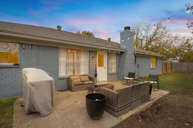 back of house featuring brick siding, fence, an outdoor living space, and a patio