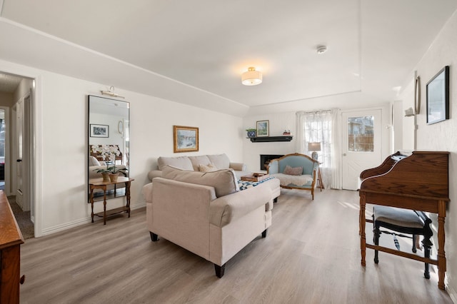 living area featuring light wood-type flooring, a fireplace, and baseboards