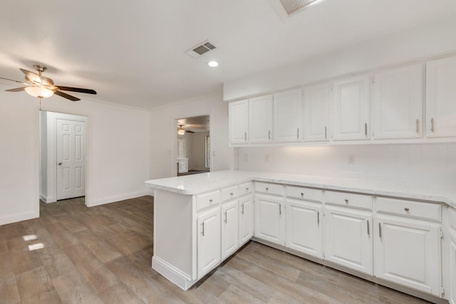 kitchen with light countertops, visible vents, backsplash, light wood-type flooring, and a peninsula