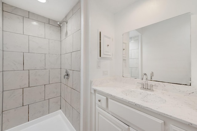 bathroom with tiled shower and vanity